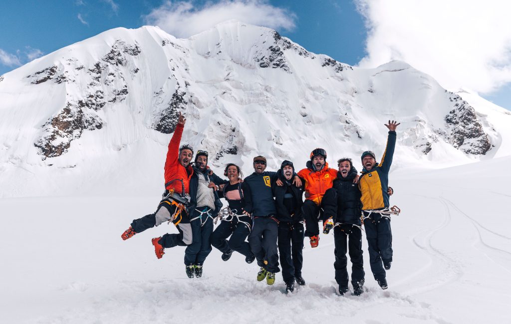 Mountaineers jumping up and cheering in the snow-capped mountains